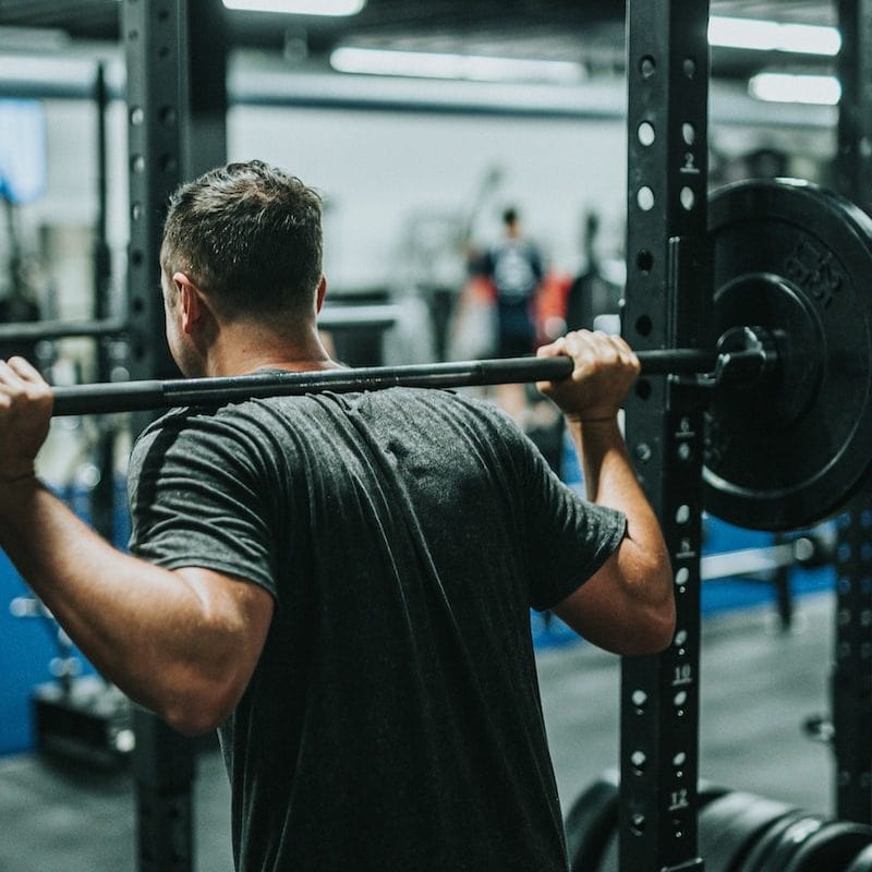 man in black t-shirt carrying barbell