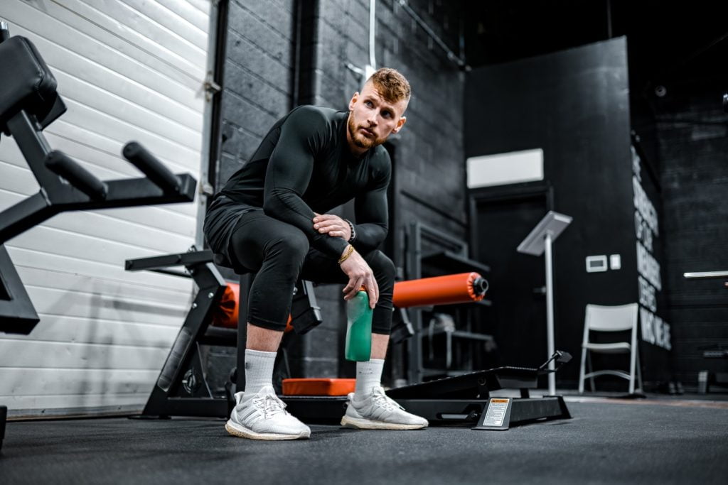 man in black long sleeve shirt and black pants sitting on exercise equipment