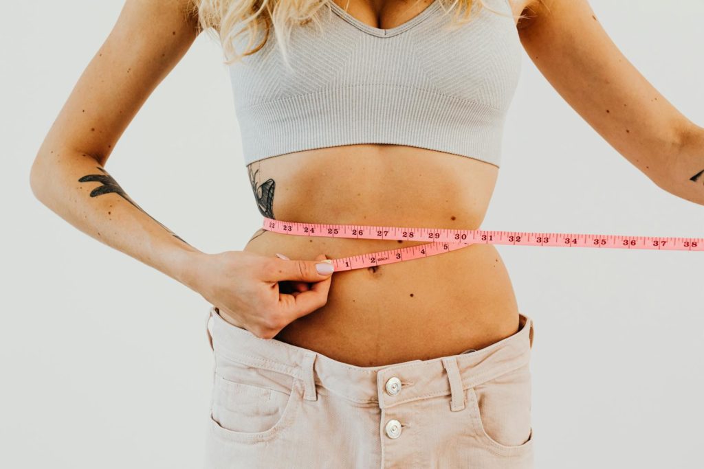 Muscu calories: Combien de calories brule-t-on lors d'une séance de musculation ? 6 Woman in Loose Denim Measuring Her Waistline