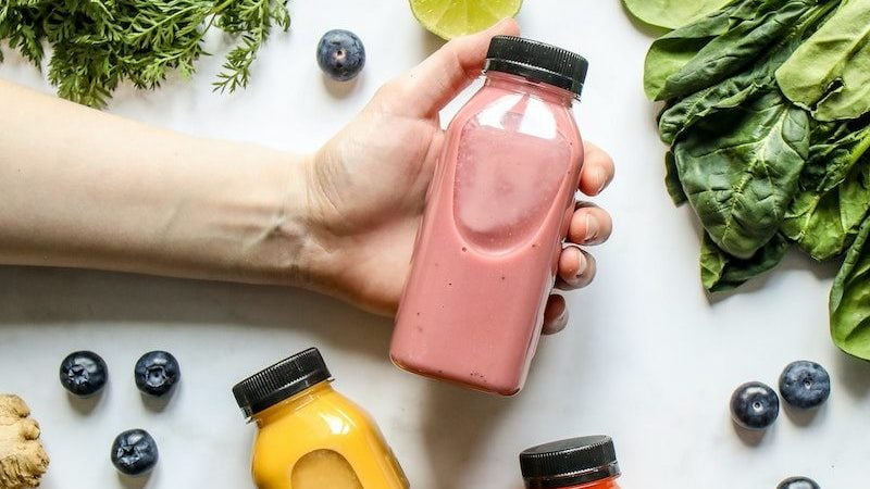 Le Guide complet de prise de masse musculaire 10 Person Holding Bottle of Smoothie Beside Green Leaves, Carrots and Berries