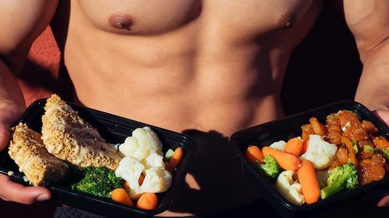 topless man in black shorts holding cooked food