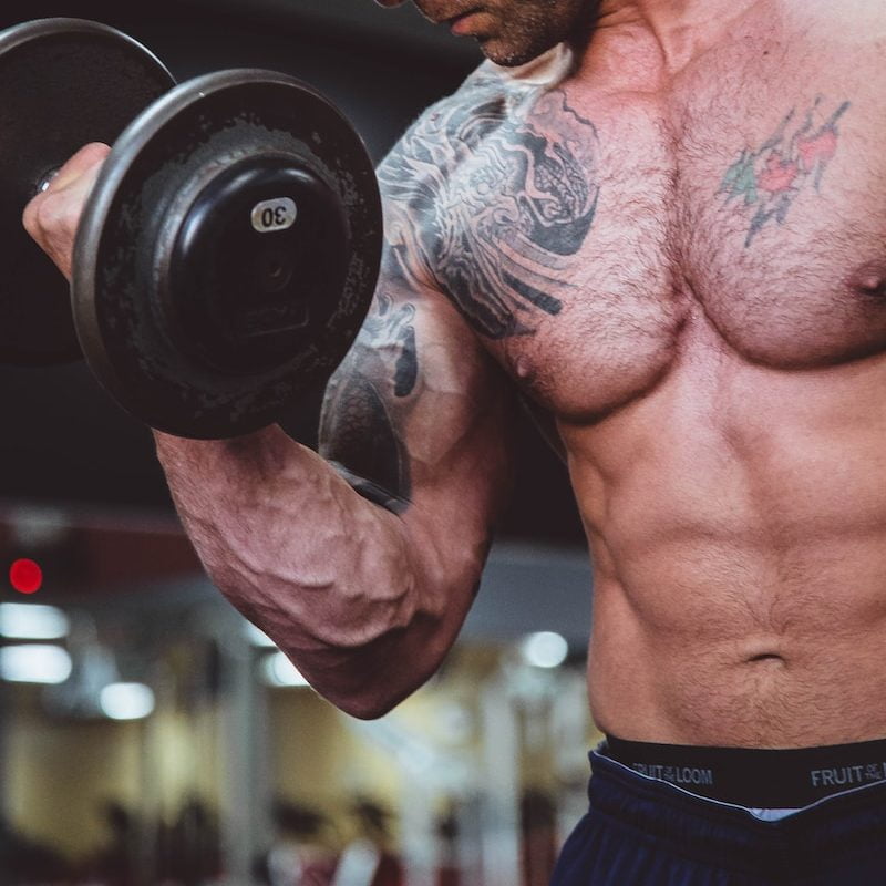 topless man holding black dumbell on right hand