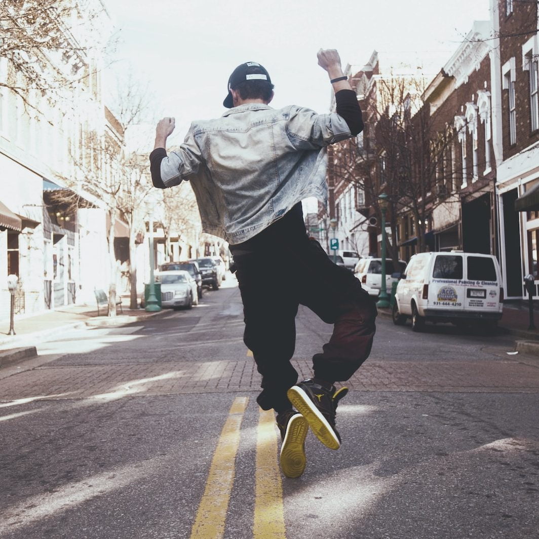 man jumping on the middle of the street during daytime