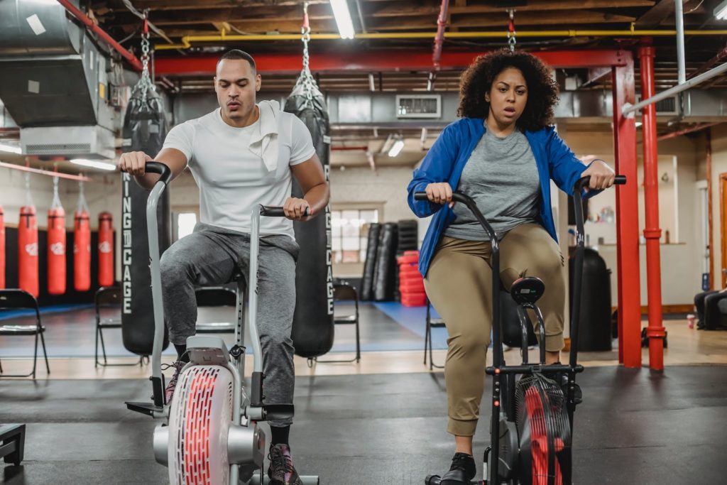 10 choses que j'aurais aimées savoir avant de commencer la musculation 6 Full body of focused curvy female and muscular male instructor training on exercise bikes in spacious gym