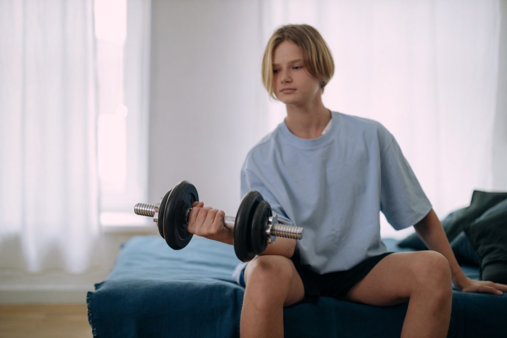Musculation à tout âge 4 A Young Man Sitting on the Bed while Holding a Barbell