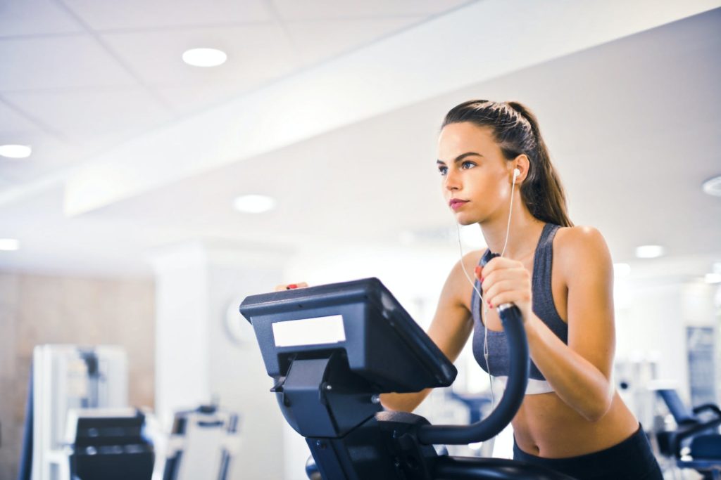 Playlist sport: notre top 8 pour rester motivé 2 Serious fit woman in earphones and activewear listening to music and running on treadmill in light contemporary sports center
