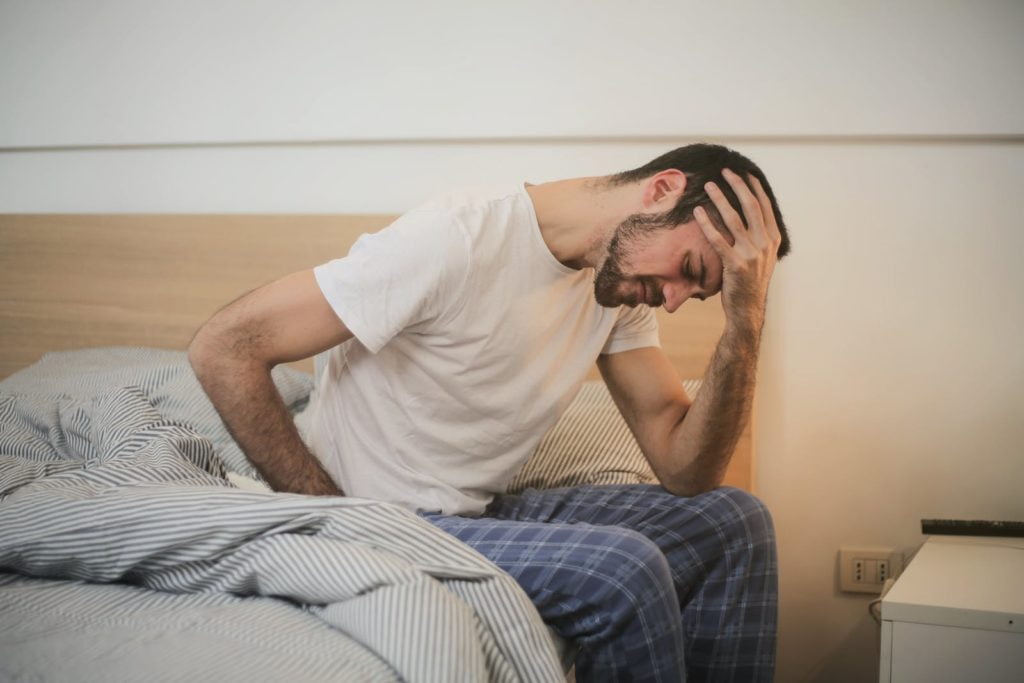 Creatine effets secondaire et dangers : la vérité 4 Young man in sleepwear suffering from headache in morning